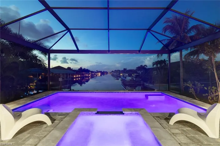 Pool at dusk featuring glass enclosure and a patio area