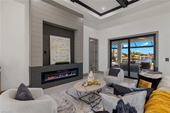 Living room with a water view, a large fireplace, crown molding, and beamed ceiling