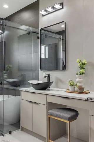 Bathroom featuring a shower with shower door and vanity