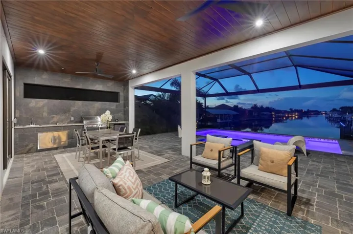 View of patio featuring outdoor lounge area, ceiling fan, glass enclosure, and a water view