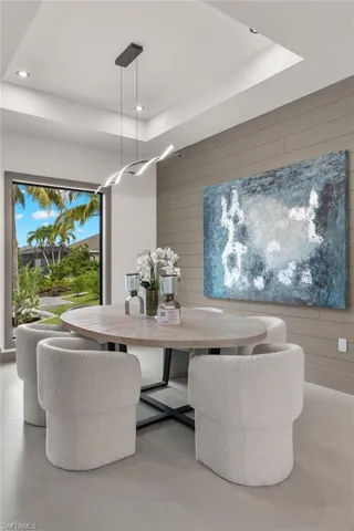 Dining room with concrete floors, wooden walls, and a tray ceiling