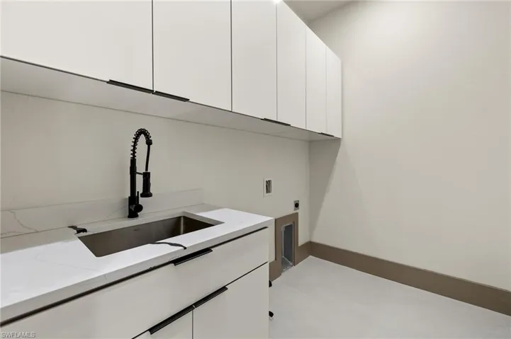 Washroom with hookup for a washing machine, hookup for an electric dryer, cabinets, and sink