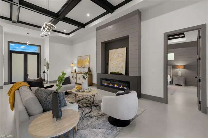 Living room with coffered ceiling, a large fireplace, and beamed ceiling