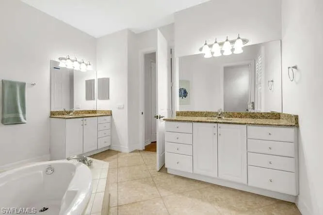 Bathroom featuring two vanities, separate tub and shower
