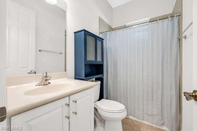 Bathroom featuring toilet, vanity, tile patterned floors, and curtained shower