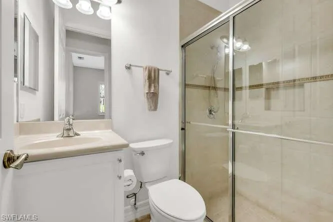 Full bathroom featuring a shower stall, toilet, and vanity