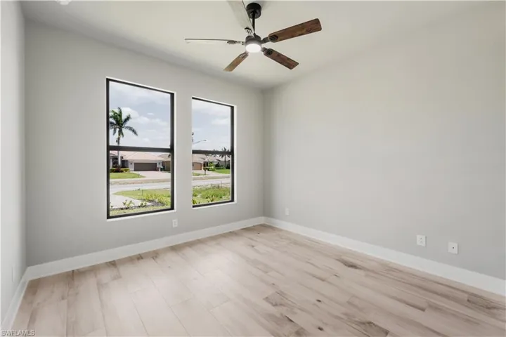 Unfurnished room featuring baseboards, a ceiling fan, and light wood-style floors