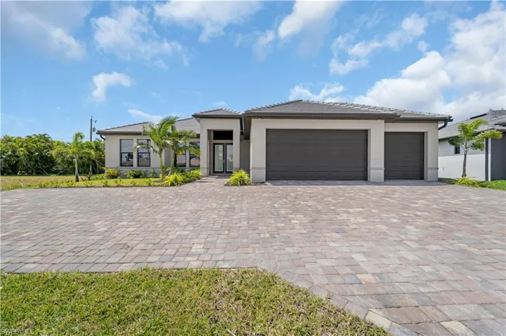 Prairie-style home featuring a garage, decorative driveway, and stucco siding