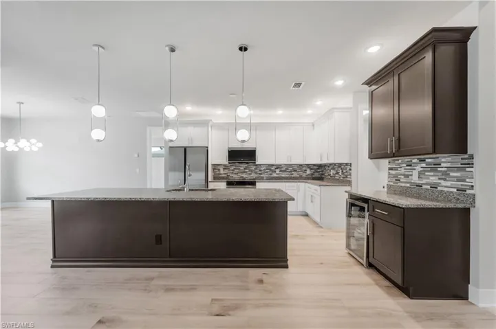 Kitchen featuring dark brown cabinets, tasteful backsplash, appliances with stainless steel finishes, and beverage cooler