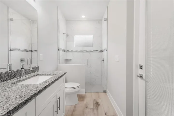 Pool Bath toilet, vanity, baseboards, and a marble finish shower