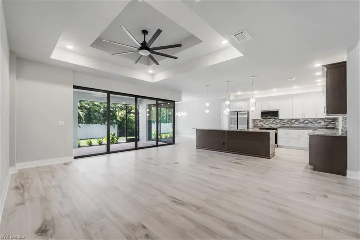 Unfurnished living room featuring recessed lighting, a raised ceiling, light wood-style floors, visible vents, and ceiling fan