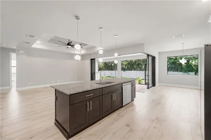 Kitchen with stainless steel dishwasher, open floor plan, baseboards, and a sink