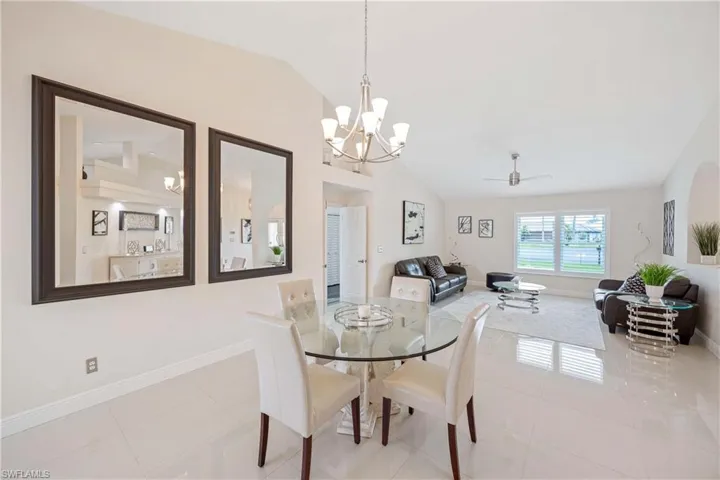 Dining area with lofted ceiling, a ceiling fan, light tile patterned floors, and a chandelier