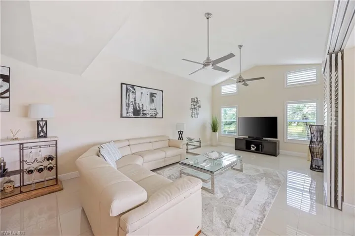 Living room featuring light tile flooring, a ceiling fan, and high vaulted ceiling