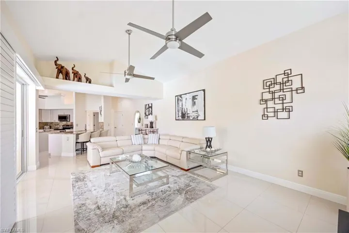 Living room with light tile patterned flooring, ceiling fan, and lofted ceiling