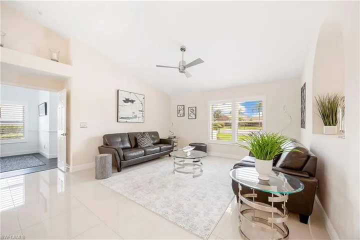 Living area with light tile patterned floors, plenty of natural light, vaulted ceiling, and ceiling fan