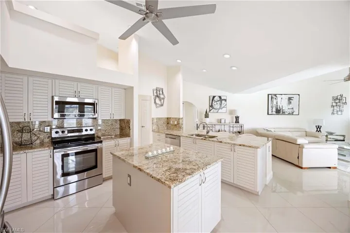 Kitchen featuring ceiling fan, stainless steel appliances, a peninsula, backsplash, and open floor plan