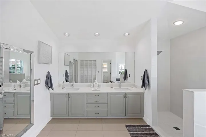 Bathroom featuring double vanity, light tile patterned floors, walk in shower, and recessed lighting