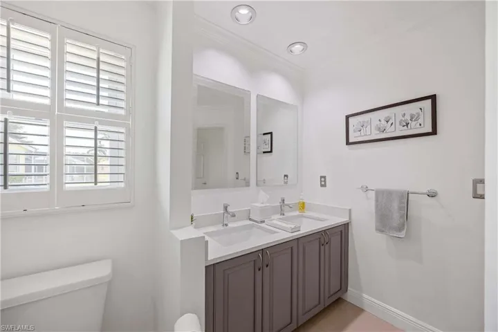 Full bathroom with double vanity, crown molding, and light tile patterned floors
