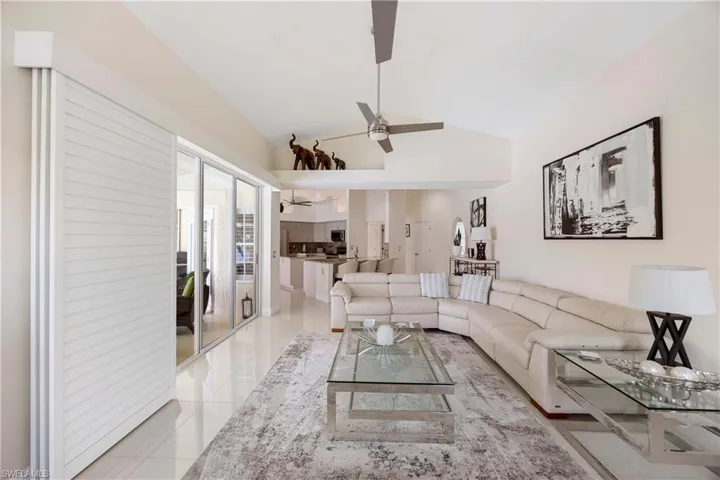 Living area featuring light tile patterned floors, lofted ceiling, and a ceiling fan