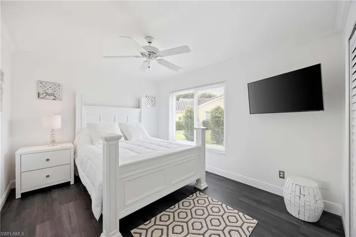 Bedroom featuring ornamental molding, dark wood-style floors, and a ceiling fan