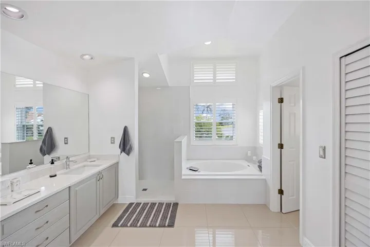 Full bath featuring a bath, light tile patterned floors, vanity, walk in shower, and recessed lighting