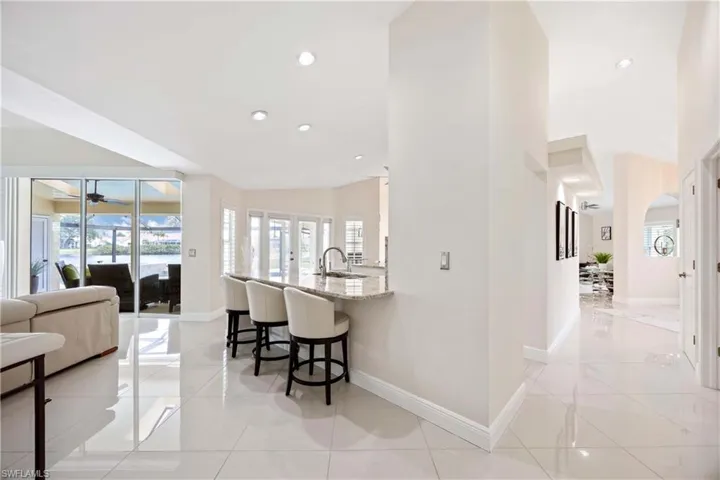 Kitchen with light stone counters, a kitchen breakfast bar, healthy amount of natural light, open floor plan, and recessed lighting