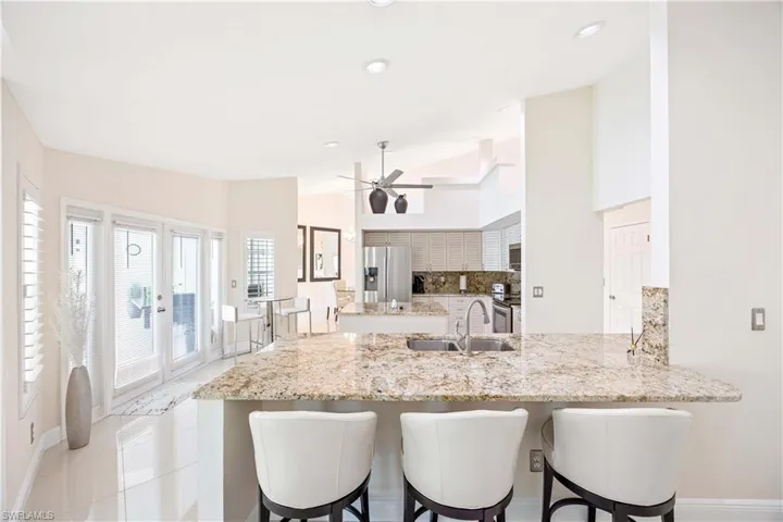 Kitchen with a peninsula, light stone countertops, a breakfast bar area, stainless steel appliances, and decorative backsplash