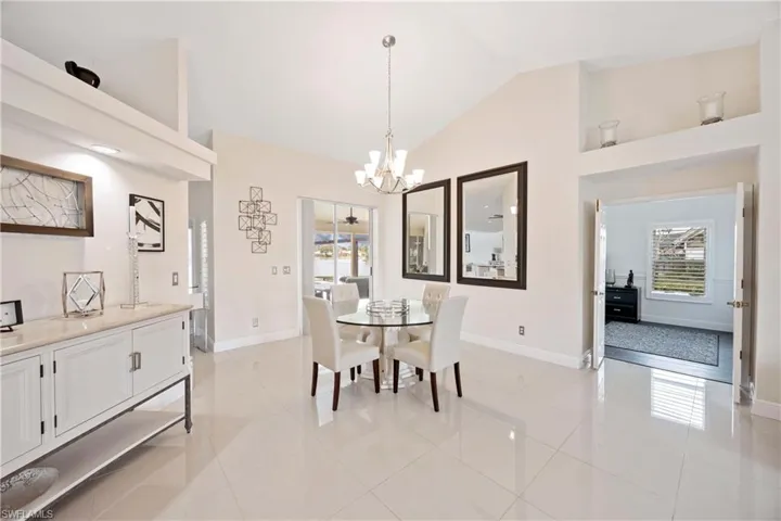 Dining area featuring vaulted ceiling, plenty of natural light, a chandelier, and light tile
