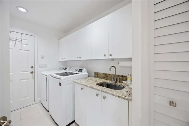 Washroom featuring cabinet space, washing machine and clothes dryer, and light tile patterned floors
