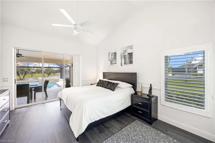 Bedroom with access to exterior, dark wood-type flooring, ceiling fan, high vaulted ceiling, and a sunroom