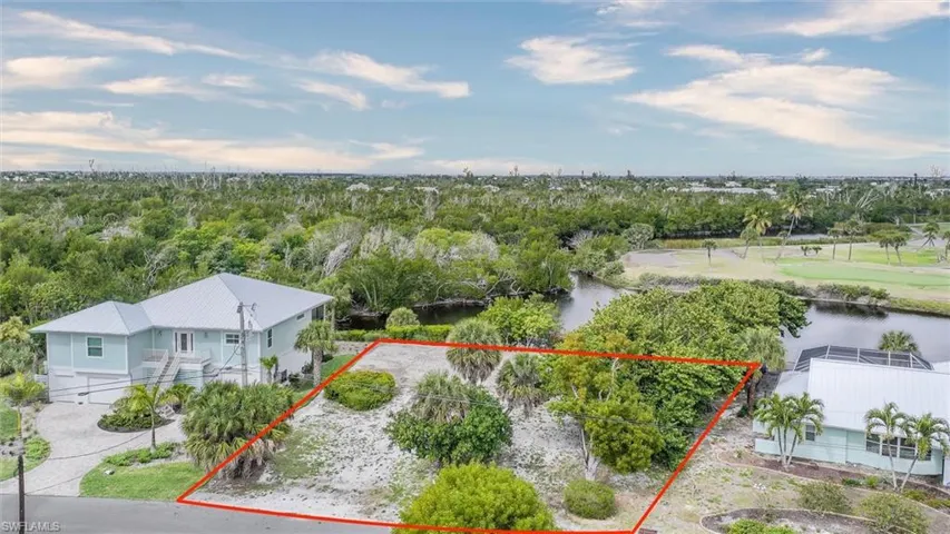 Aerial view of property and surrounding area featuring property parcel outlined and a nearby body of water
