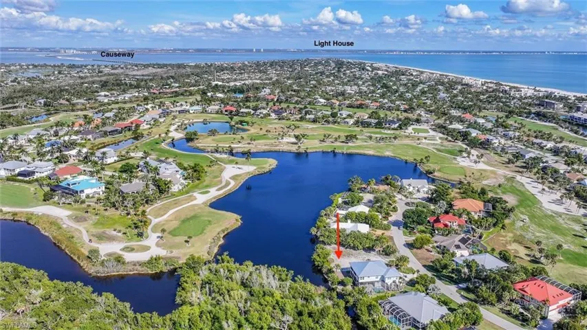 Aerial perspective of suburban area featuring a nearby body of water and a local golf course