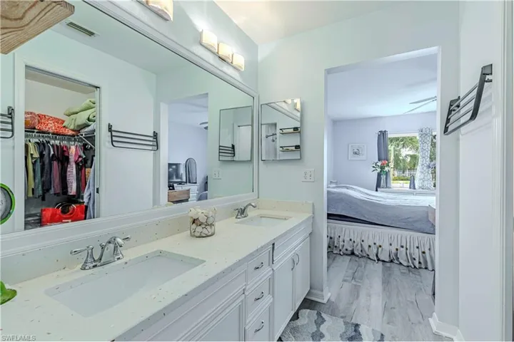 Bathroom with double vanity, light wood finished floors, ensuite bathroom, and a walk in closet