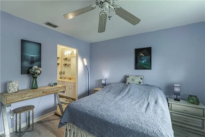 Bedroom featuring wood finished floors, ceiling fan, and ensuite bathroom