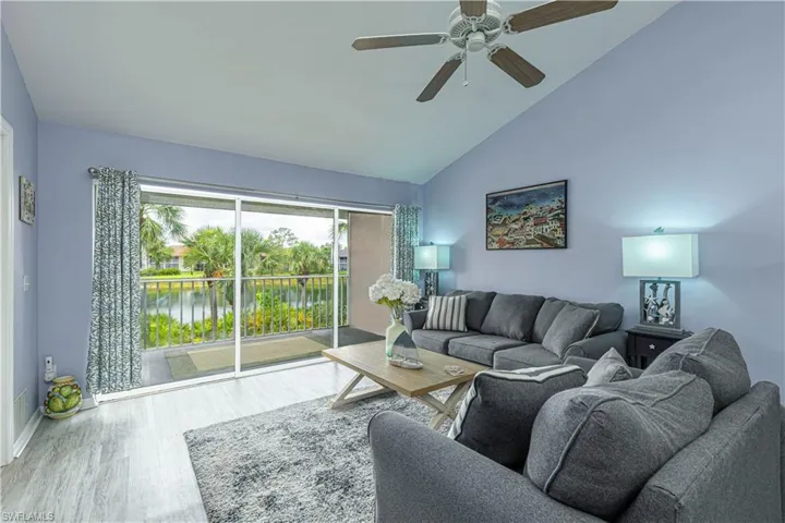 Living area with a water view, wood finished floors, a ceiling fan, and high vaulted ceiling