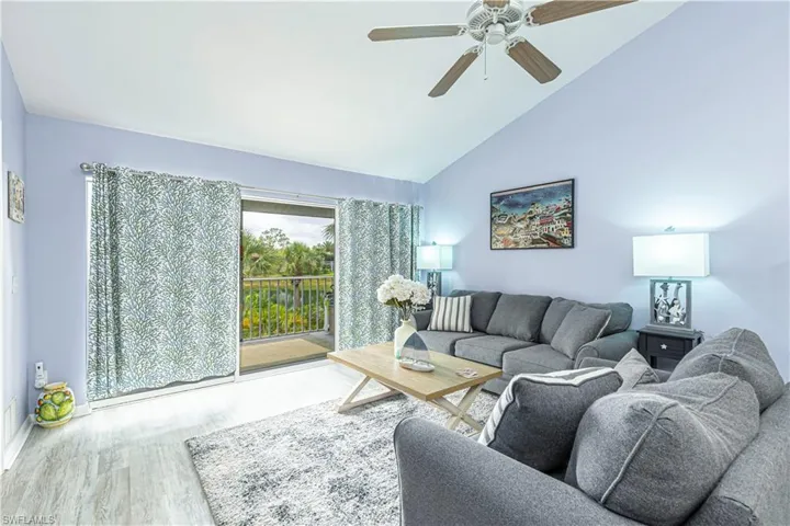 Living room with wood finished floors, ceiling fan, and high vaulted ceiling