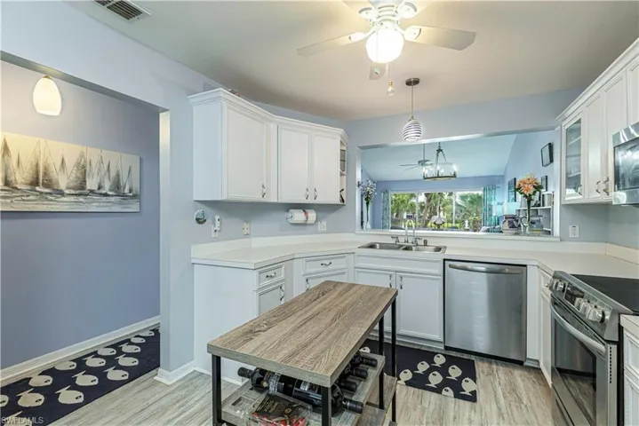 Kitchen with a ceiling fan, stainless steel appliances, light countertops, and white cabinetry