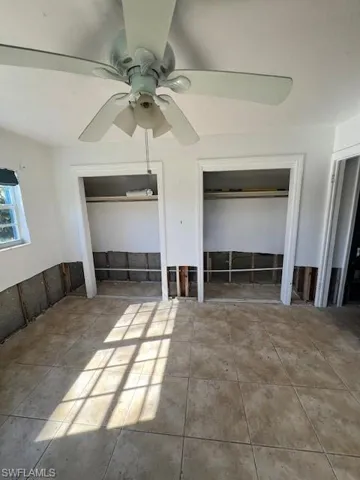 Unfurnished bedroom with two closets and ceiling fan