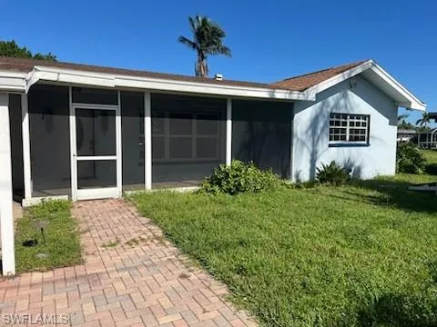 Rear view of house with a sunroom and a yard