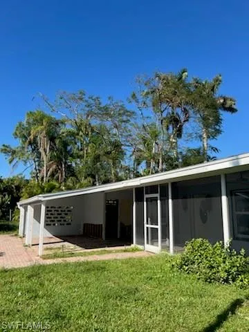Back of property featuring a sunroom and a lawn