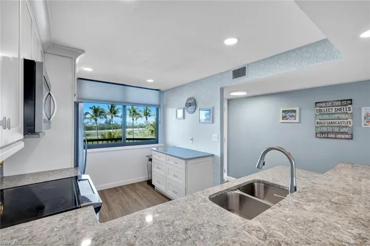 Kitchen features stone countertops, stainless steel microwave, a sink, and electric range oven