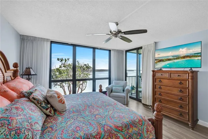 Bedroom with expansive windows, a ceiling fan, light wood finished floors, a textured ceiling, and access to outside