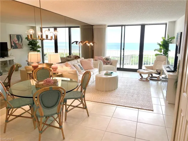 Living room with a chandelier, light tile patterned floors, floor to ceiling windows, plenty of natural light, and a textured ceiling