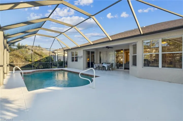 View of pool with ceiling fan, a patio area, and glass enclosure