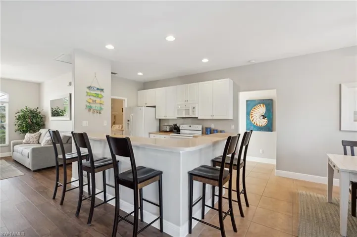 Kitchen with white cabinets, a breakfast bar, and white appliances.