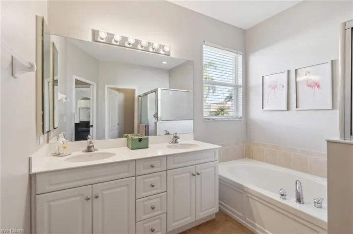 Bathroom with tile patterned floors, vanity with dual sinks, and independent shower and garden tub.