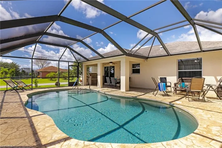 Outdoor pool featuring a patio area, a ceiling fan, and glass enclosure