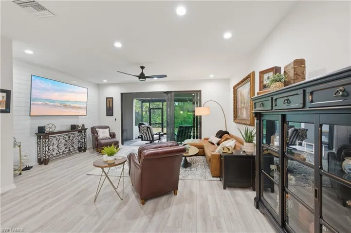 Living room with ceiling fan, light wood finished floors, recessed lighting, and wood walls