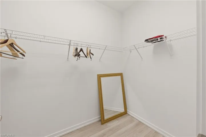 Walk in closet with light wood finished floors